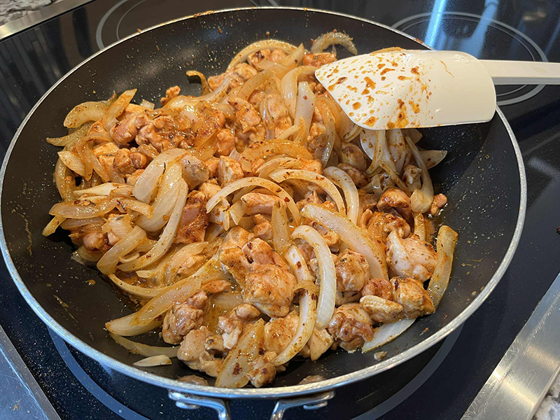 Cubed chicken, diced onions and spices cooking together in a beautiful and mouthwatering harmony.